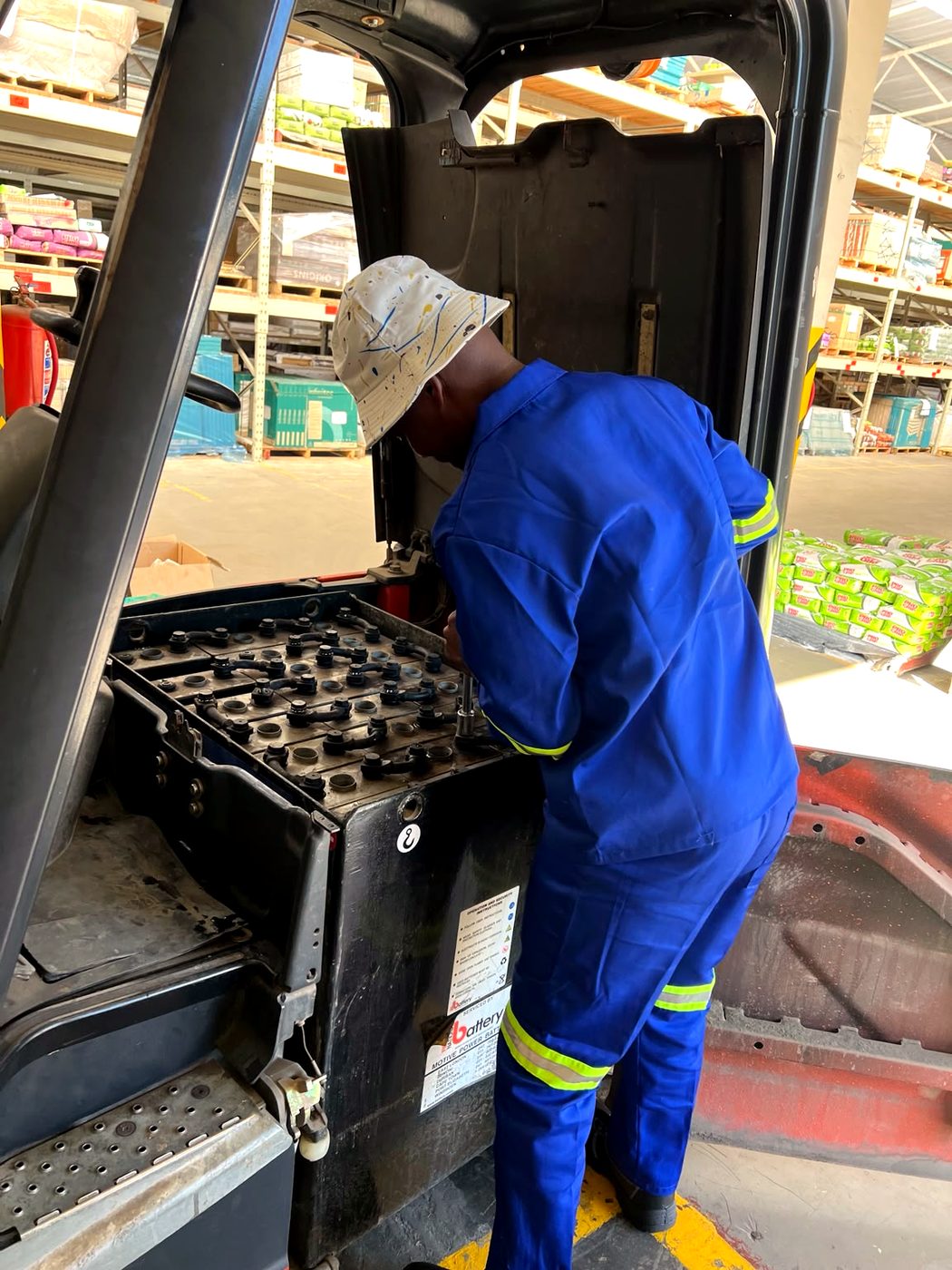 Ampwise technician inspecting a forklift battery's cell caps in a warehouse.