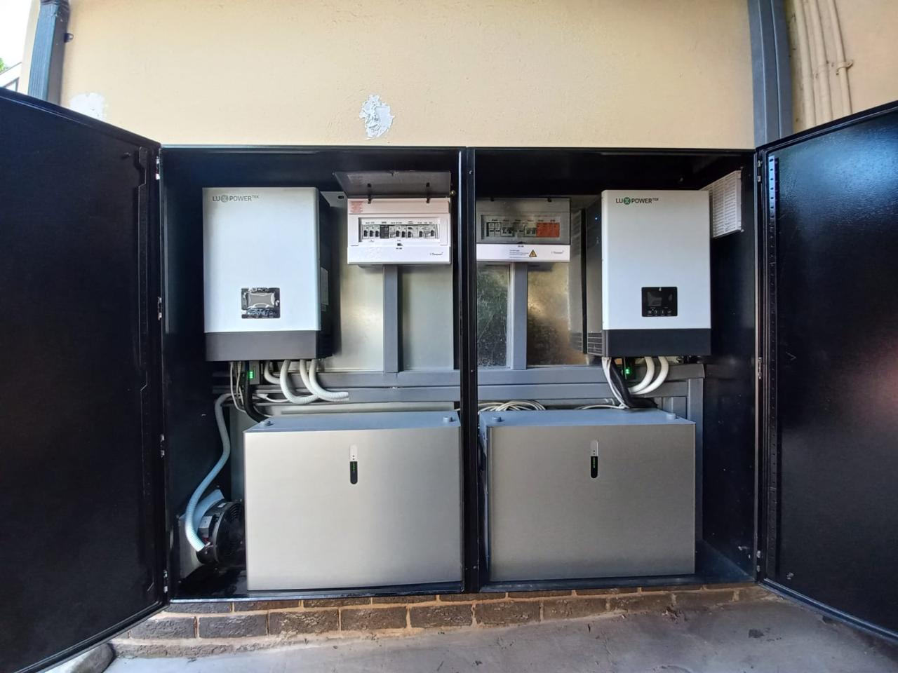 Commercial solar backup installation with two inverters and distribution boards mounted above their battery enclosures.