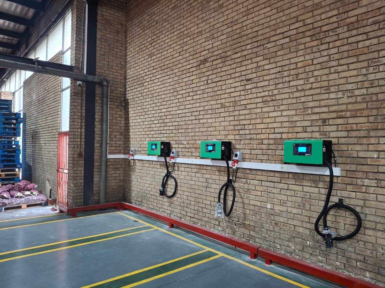Wall-mounted battery charger bay installed in a warehouse, three chargers wired and ready for a forklift fleet.