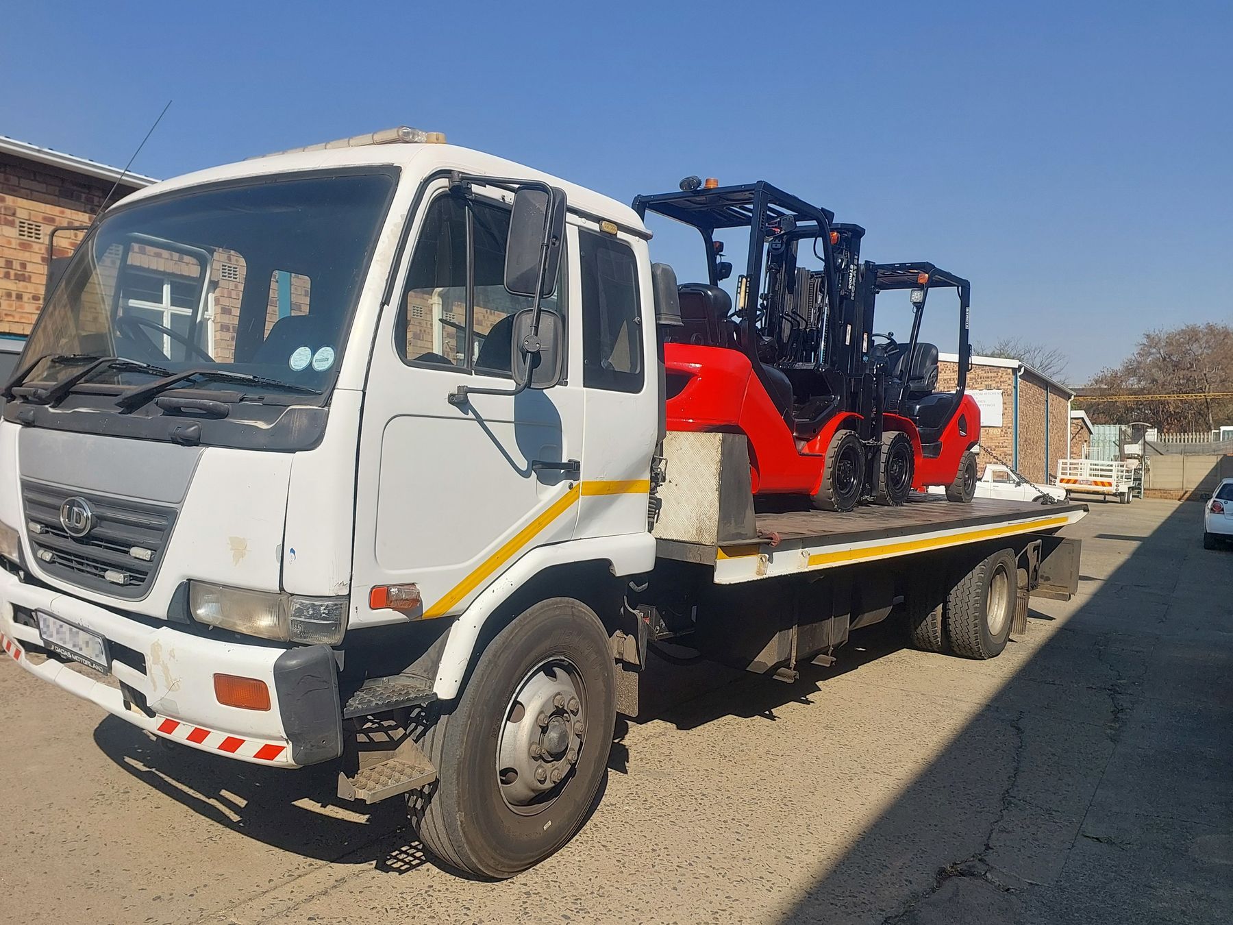 Rental forklifts loaded on an Ampwise flatbed truck for delivery to a customer site.