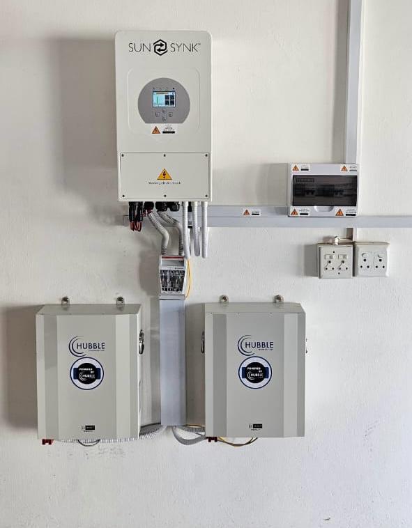 Sun-Synk inverter and Hubble lithium battery packs installed alongside a distribution board for a commercial solar backup power system.